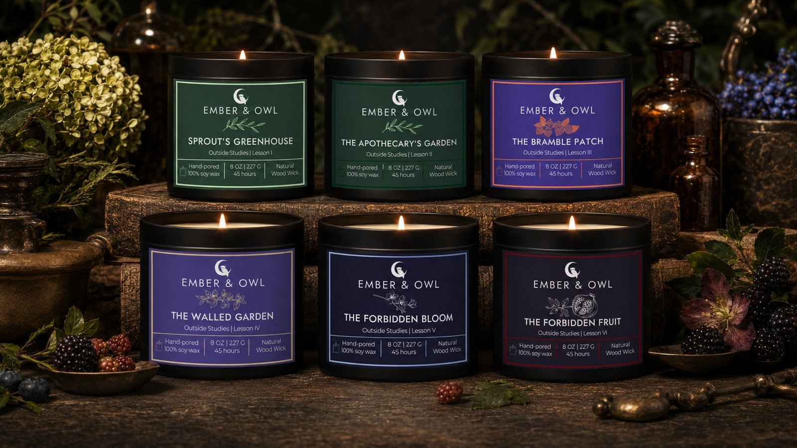 Ember and Owl Outside Studies Volume I: all six soy candles lit and displayed in two rows in a dark botanical setting, showing the final label designs — Sprout's Greenhouse, The Apothecary's Garden, The Bramble Patch, The Walled Garden, The Forbidden Bloom, and The Forbidden Fruit